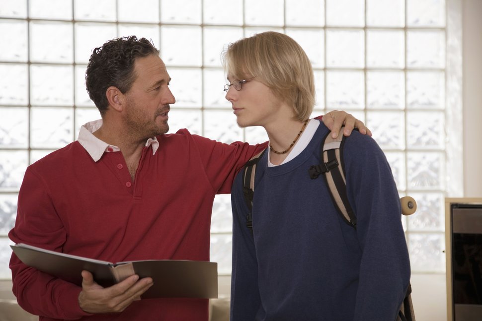 Father talking to his son with a binder of resources.