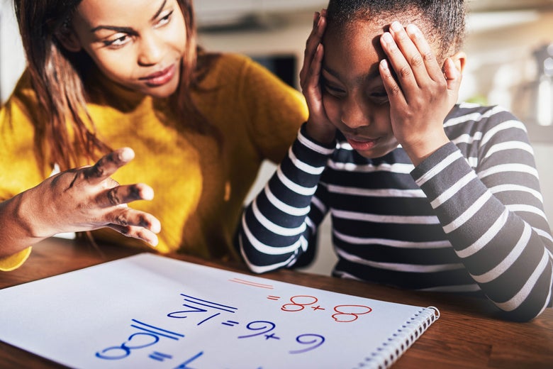 Mother helping her child with math homework at the table