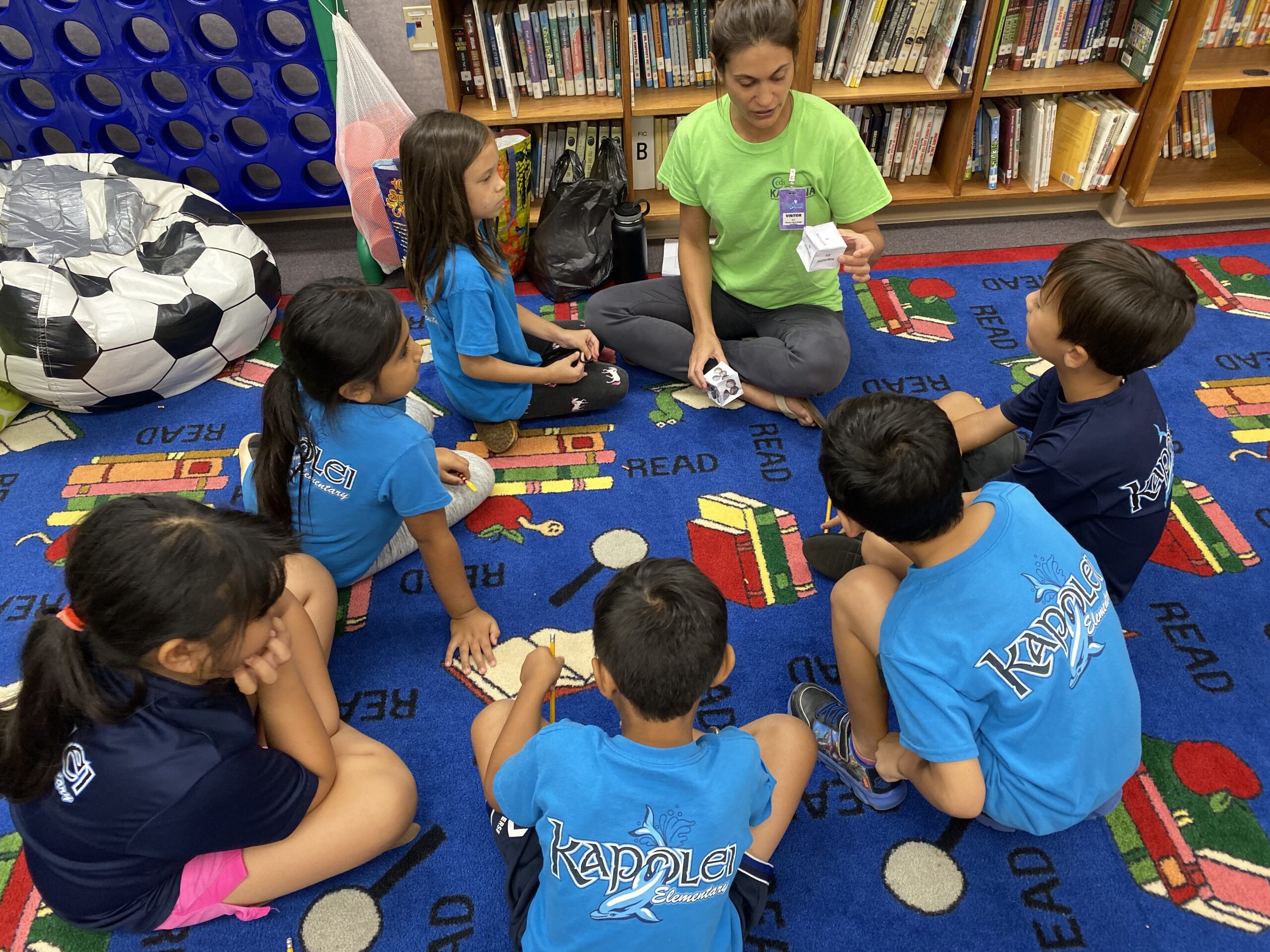 KPN2 staff sitting with KPN2 students on the floor looking at a dice manipulative to learn about telling time