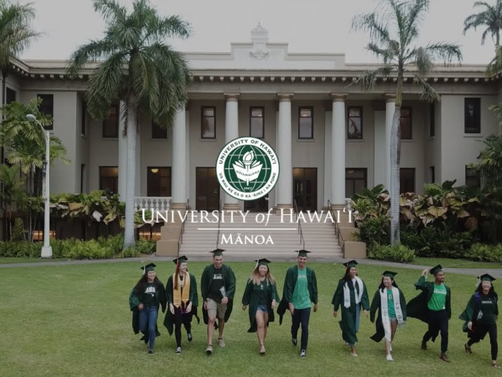 University of Hawaiʻi at Mānoa. A group of university graduates wearing gowns and caps is walking away from a large building with columns and steps.