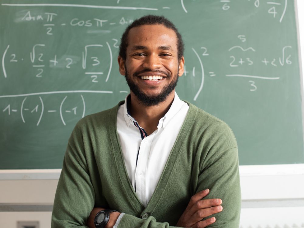 Person smiling in front of chalk board