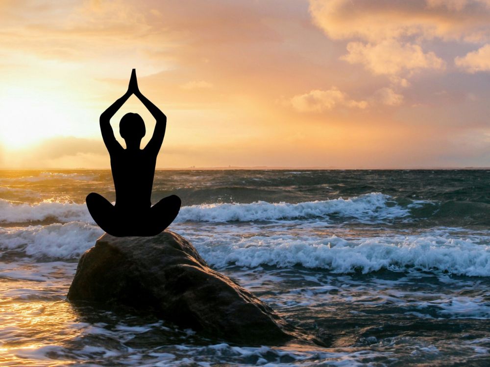 person doing yoga at the ocean