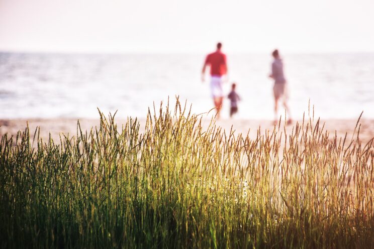 Parents and a child walking on the beach.