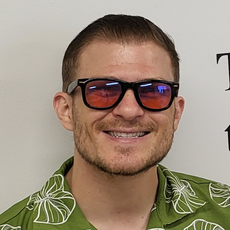 Person smiling with green short and glasses.